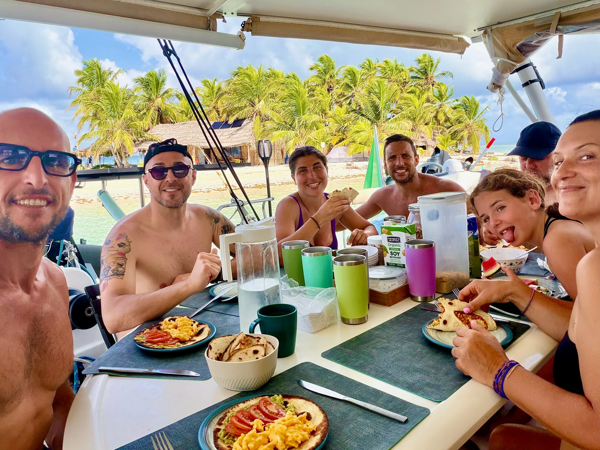 The group at breakfast around the cockpit table, the island behind them