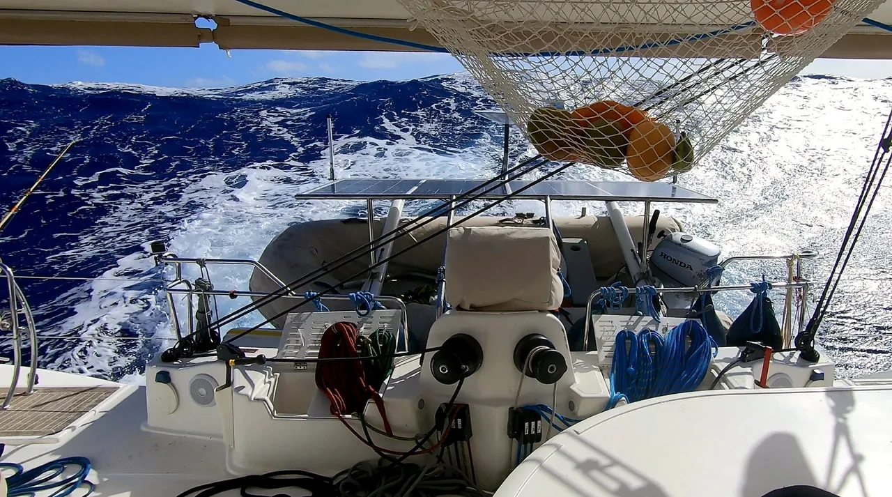 The cockpit of IKIGAI under way, the wake running astern and the fruit net