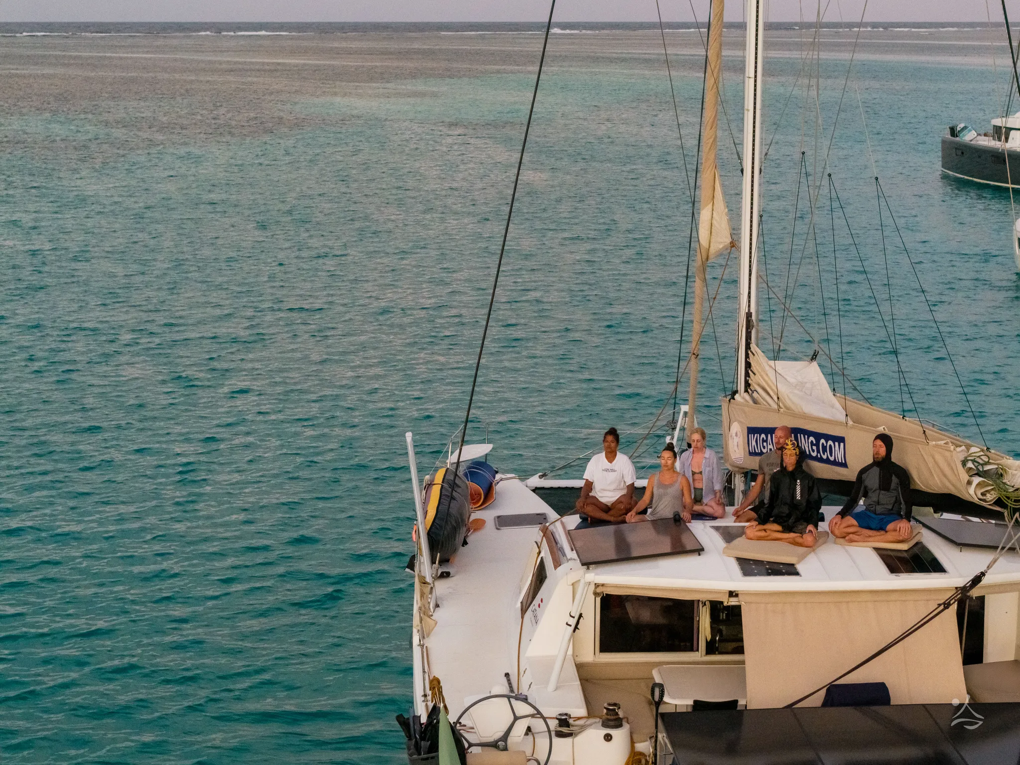 Group meditation on deck, the catamaran at anchor seen from above
