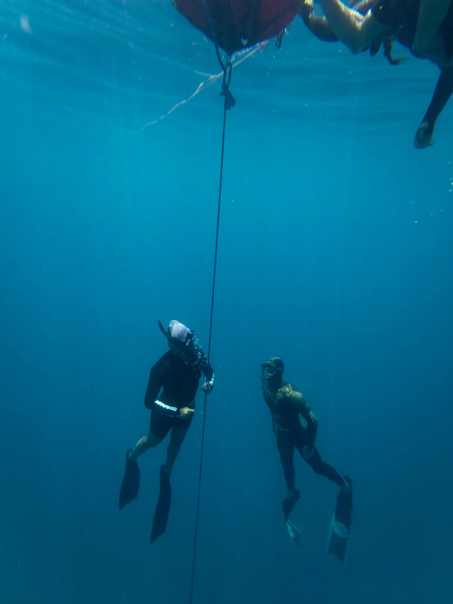 Two freedivers coming back up along the line, the buoy at the surface